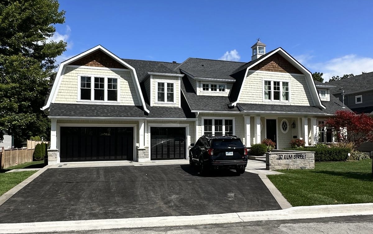 Large two-story house with white siding, black garage doors, black SUV parked in driveway, and a sign reading '37 Elm Street' on the front lawn.