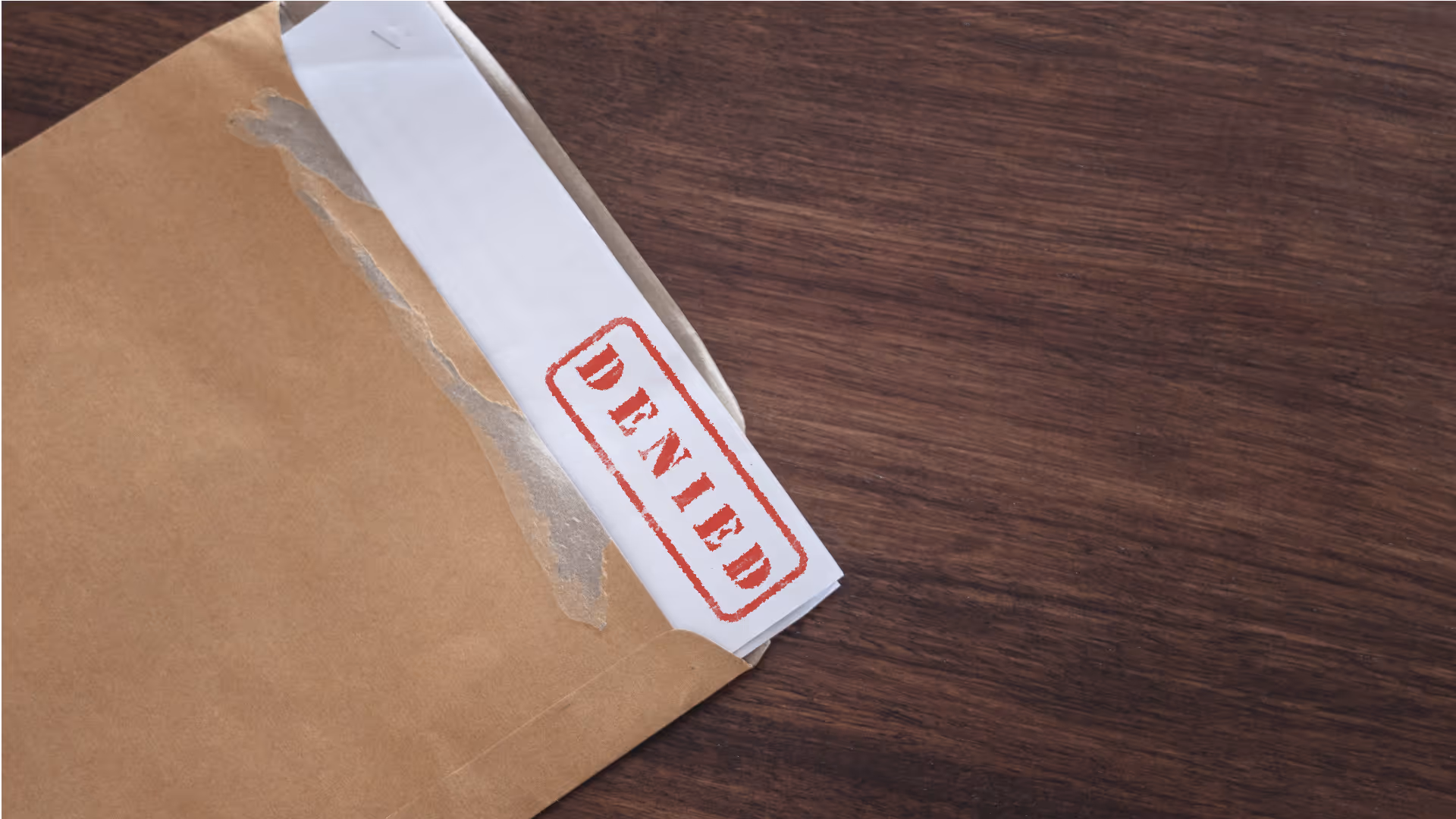 an open envelope showing part of a document with a denied stamp.