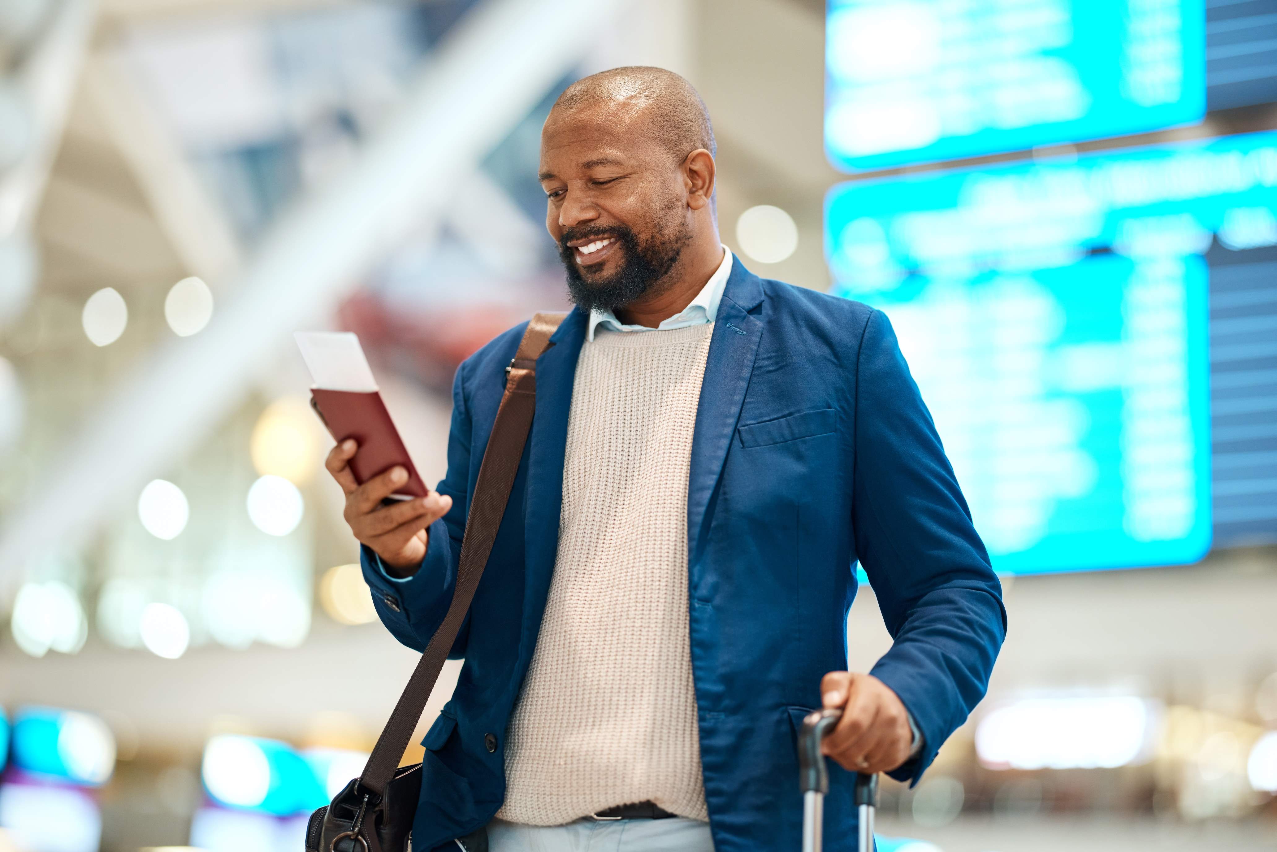 A black man in business attire at an airport looking at his passport