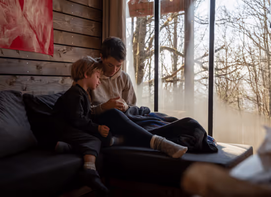 A mother reading to her child on the sofa of the cabin