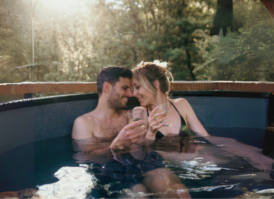 Ein Paar kuschelt im Hot Tub seiner Baumhaus mit Whirlpool während eines Urlaubs zu zweit bei Nutchel