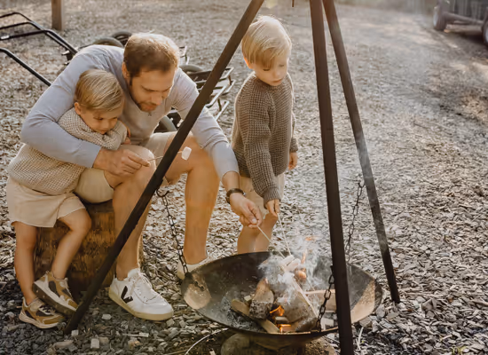 Ein Vater und seine 2 Söhne grillen S'mores in einem Last-Minute-Urlaub mit Kindern
