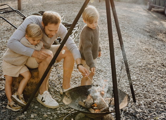 A dad and his 2 sons grilling s'mores on a last-minute holiday with kids