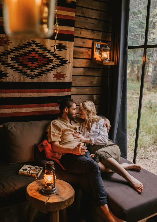 A couple cuddling on the sofa of their cabin in the woods in Alsace