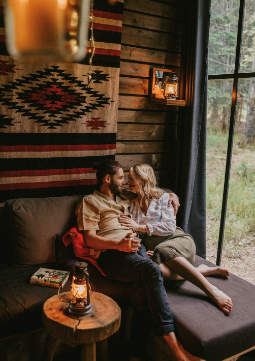 A couple cuddling on the sofa of their cabin in the woods in Alsace