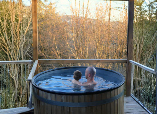 A father and his son enjoying the hot tub of a cabin with jacuzzi during winter school last-minute holidays at Nutchel