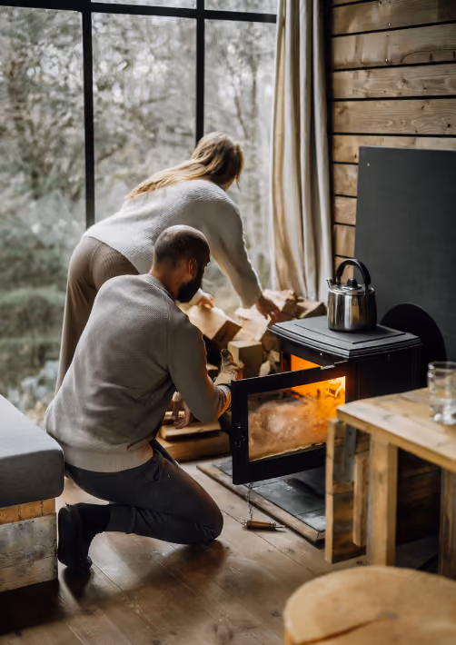 A couple setting up the fire in a cabin in the woods during their autumn break