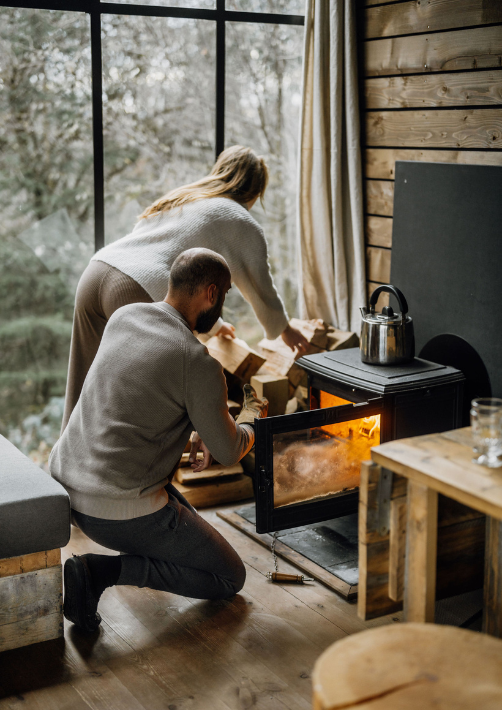 A couple setting up the fire in a cabin in the woods during their autumn break