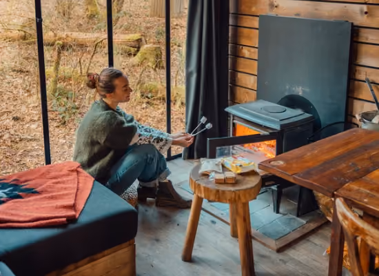 A woman roasting marshmallows in a cabin in the woods