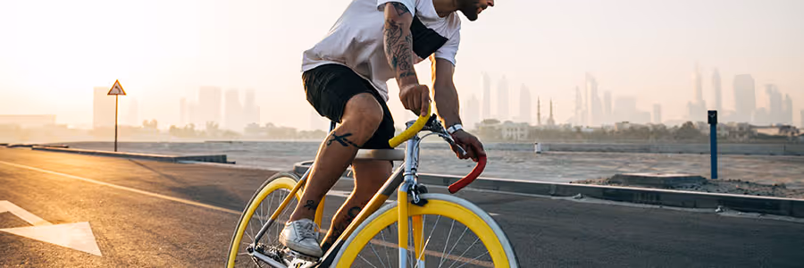 Man on bicycle on road with city in background