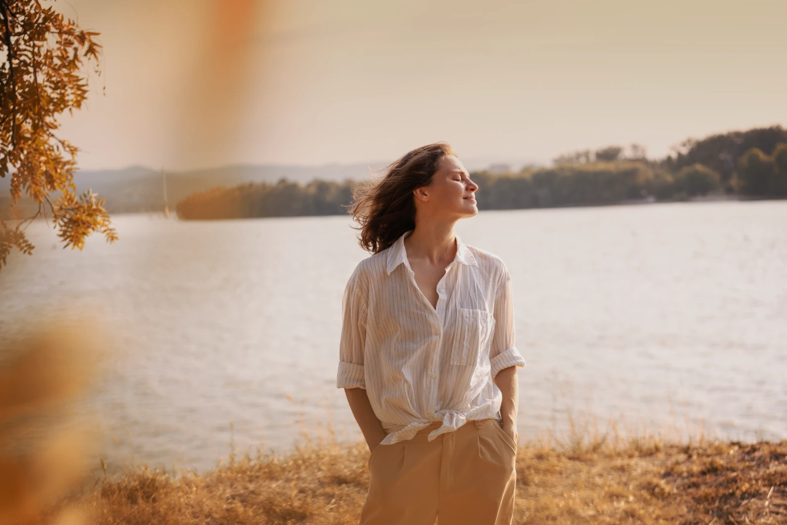 A woman standing in front of a lake during autumn