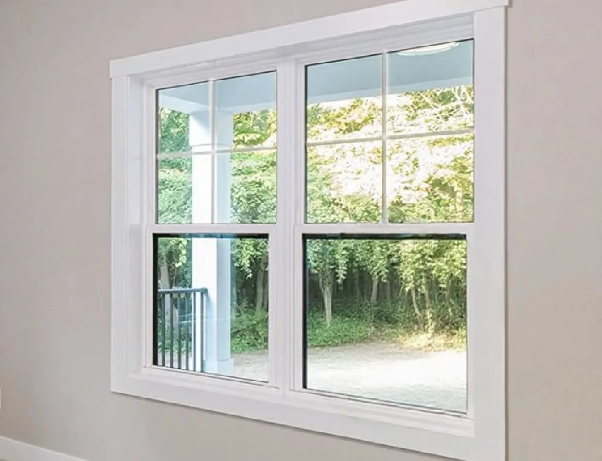 Double-hung white window with four panes showing a porch column and green trees outside.