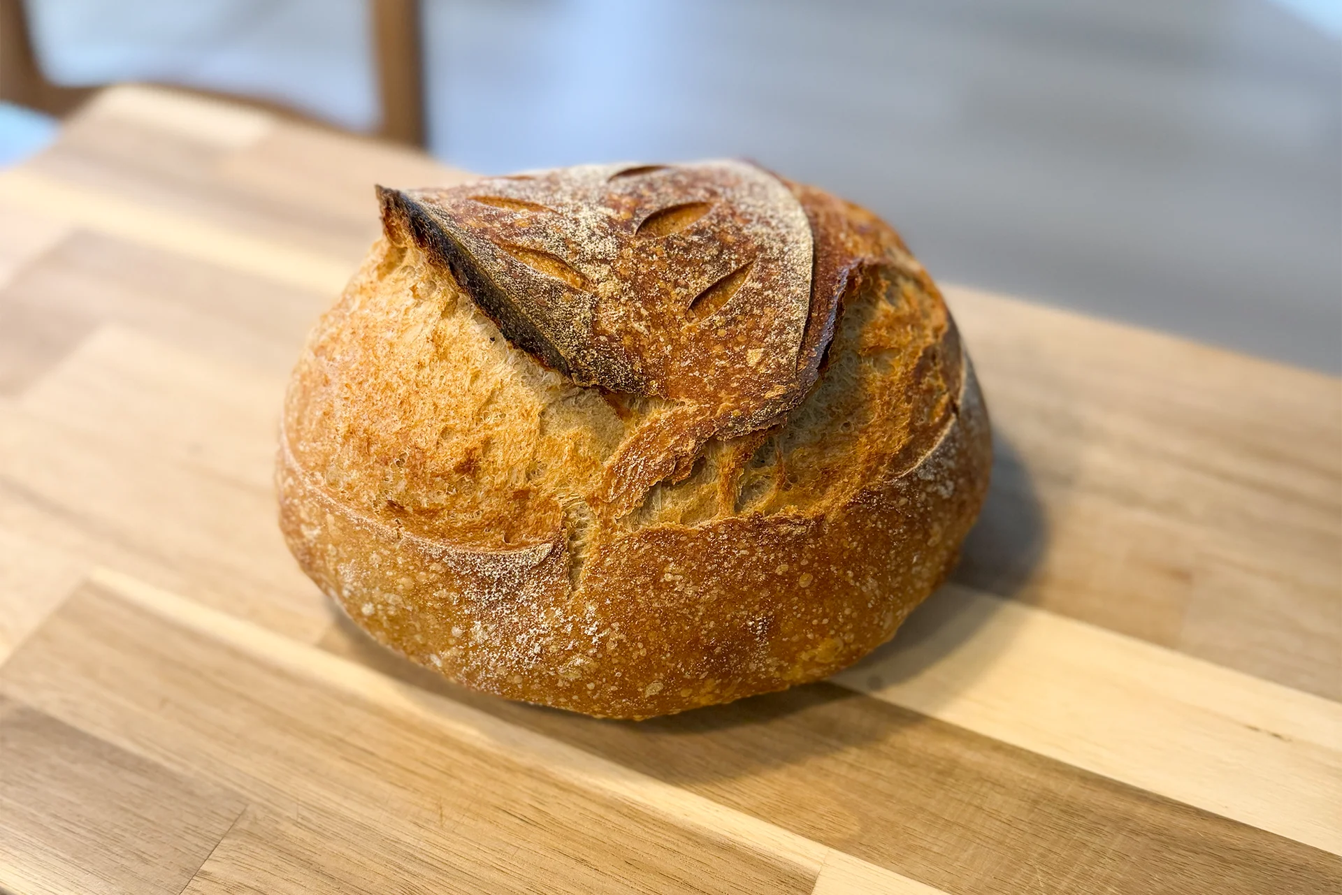 Perfectly baked artisan sourdough bread on a wooden cutting board after using ChatGPT for recipe adjustments.