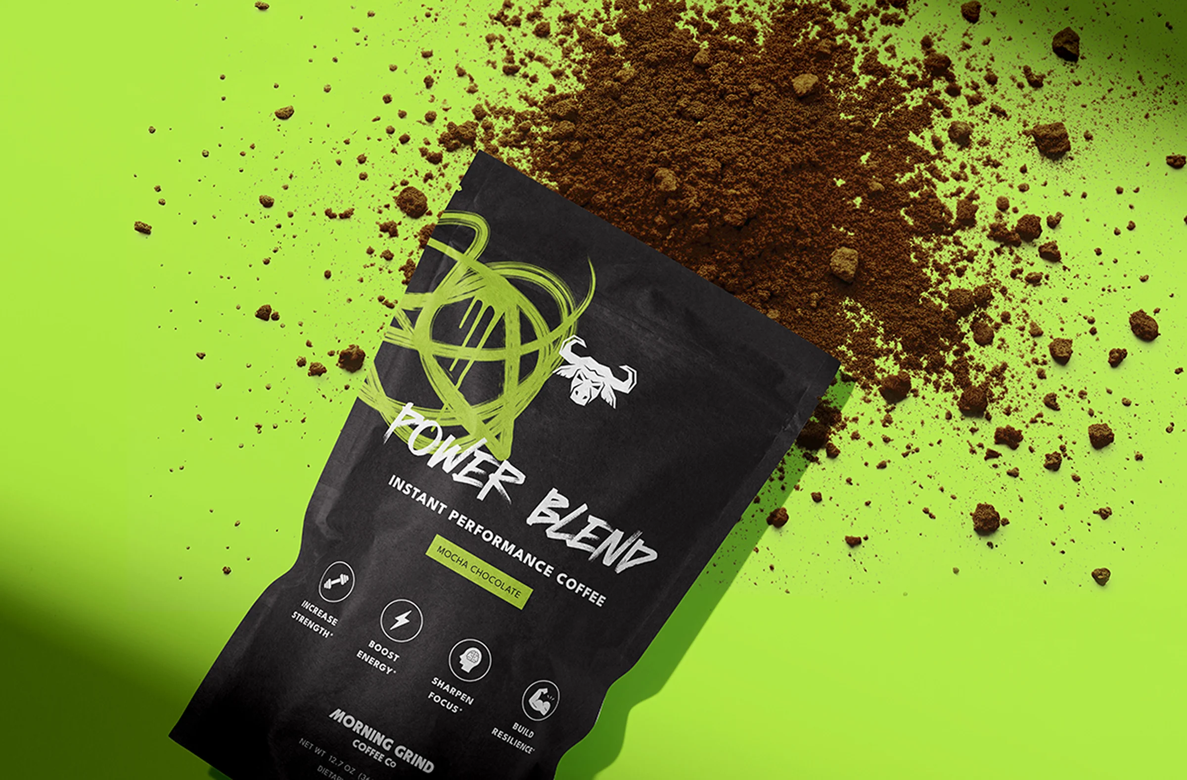 A black coffee pouch with a green paint squiggle. the words "Power Blend," and the Morning Grind Branding lay on a neon green background with some instant coffee powder spilling out of the top.