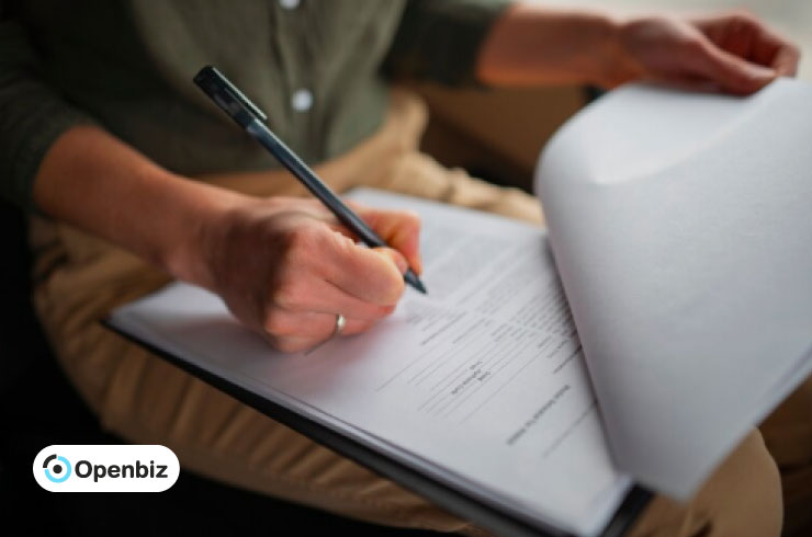 Primer plano de unas manos rellenando el formulario 1065 con un bolígrafo y papeles de una sociedad.