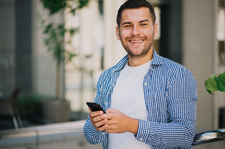 Confident freelancer holding a phone and smiling outdoors