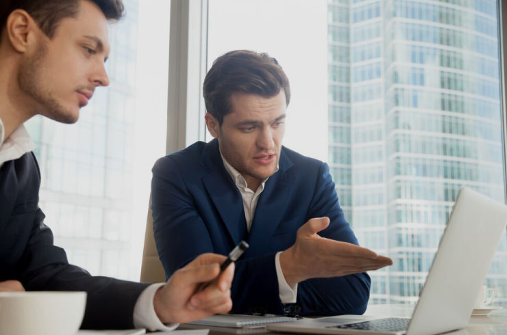 Two businessmen discussing trading strategies and funded account opportunities
