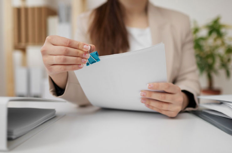 Businesswoman attaching a paperclip to IRS Form 1099 documents