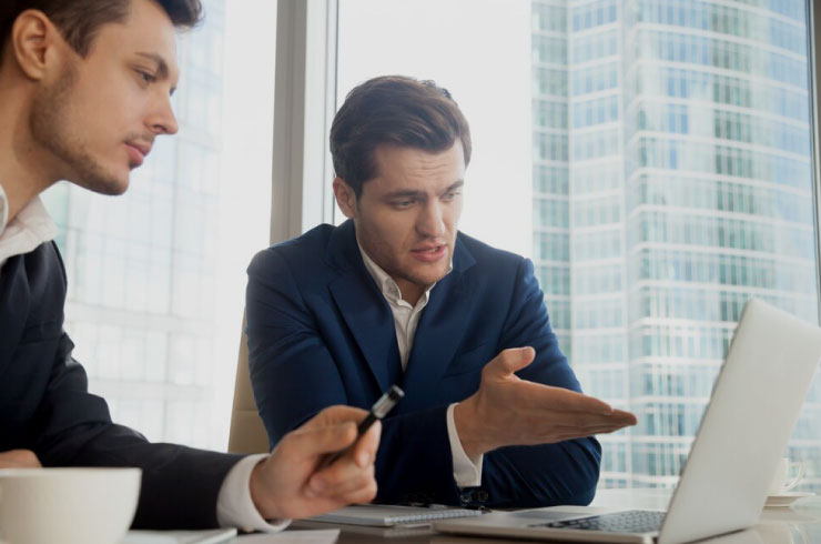 Two businessmen analyzing compound interest calculations on a laptop in a modern office