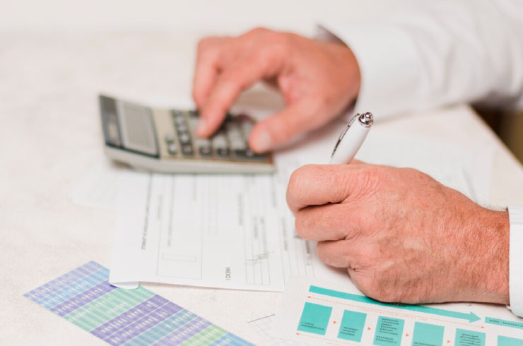 Close-up of a person calculating compound interest on a financial document with a calculator.