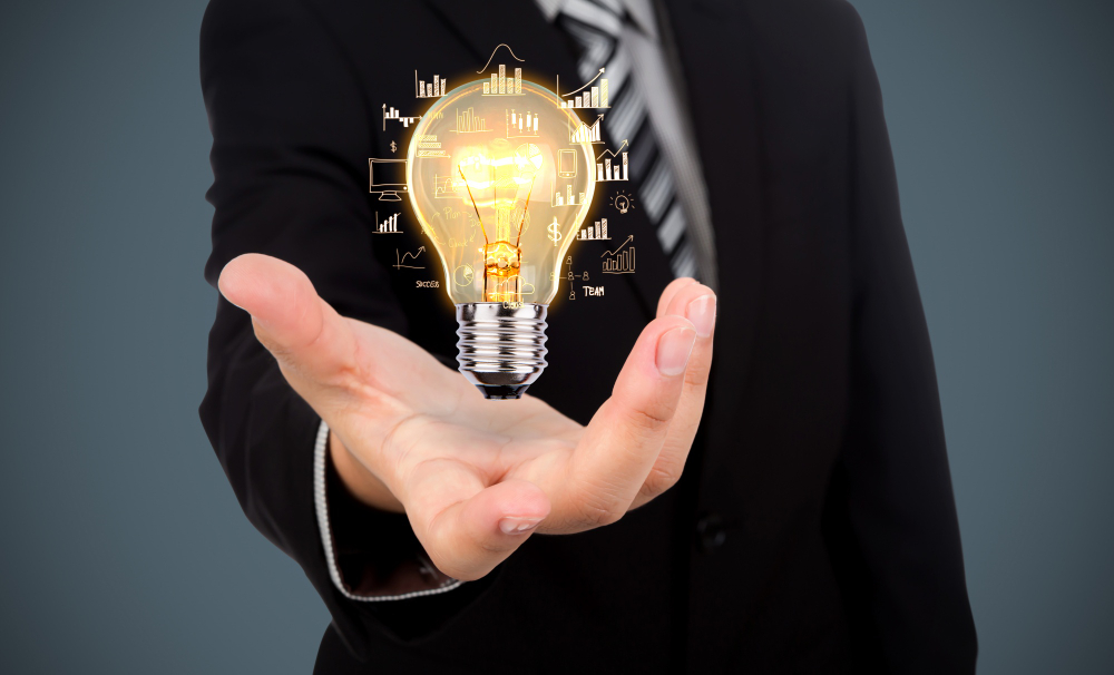 Businessman holding a glowing light bulb representing innovation and new client opportunities.