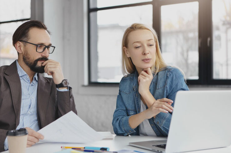 Two business professionals analyzing financial documents together, discussing revenue strategies and company performance.