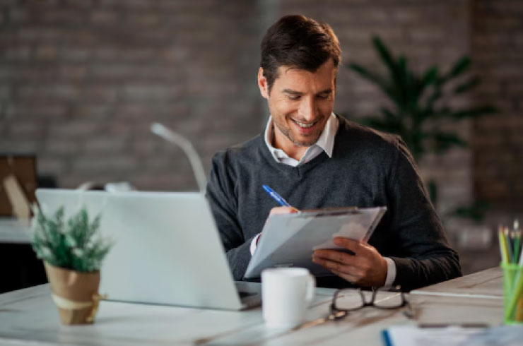 Business professional reviewing tax documents and working on IRS compliance at his desk.
