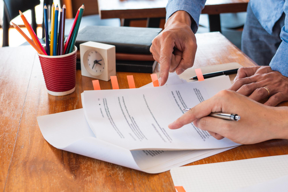 Close-up of employer signing employee work permit documents in an office setting.