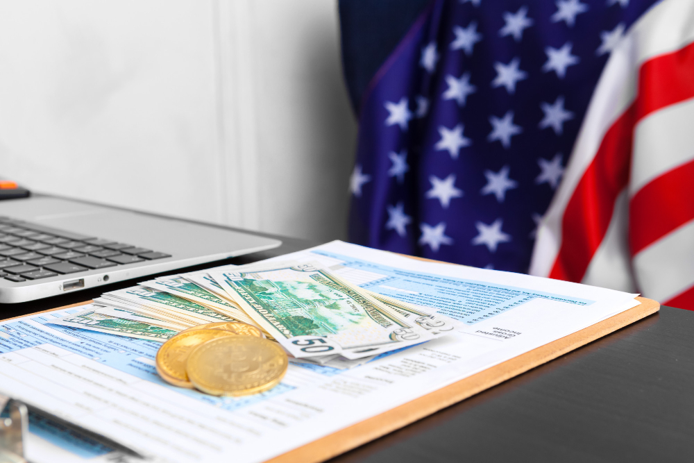 Laptop, U.S. flag, and tax papers on an office desk, illustrating financial planning and accounting compliance in the U.S.