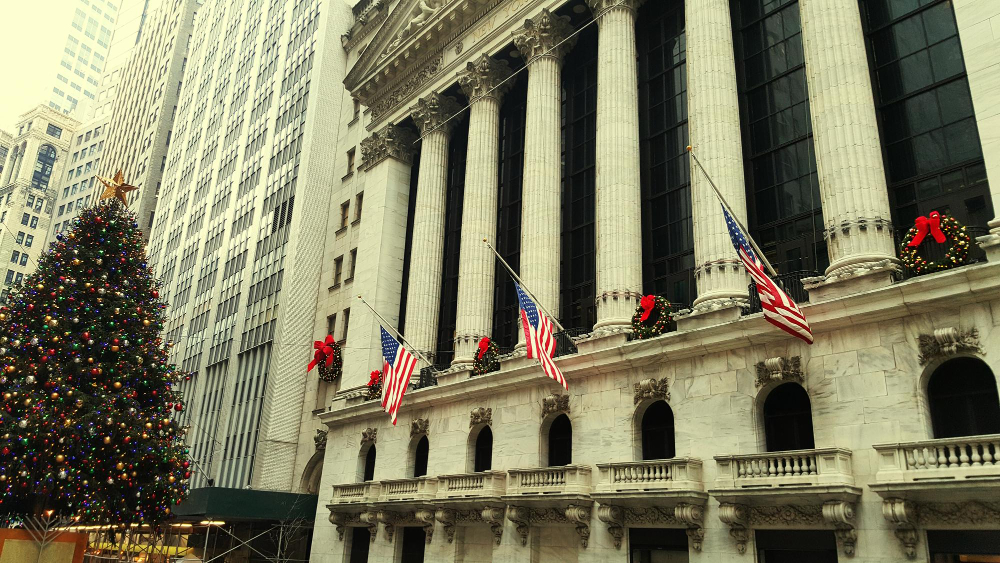 Front view of the New York Stock Exchange with U.S. flags, symbolizing the financial system overseen by the Fed USA.