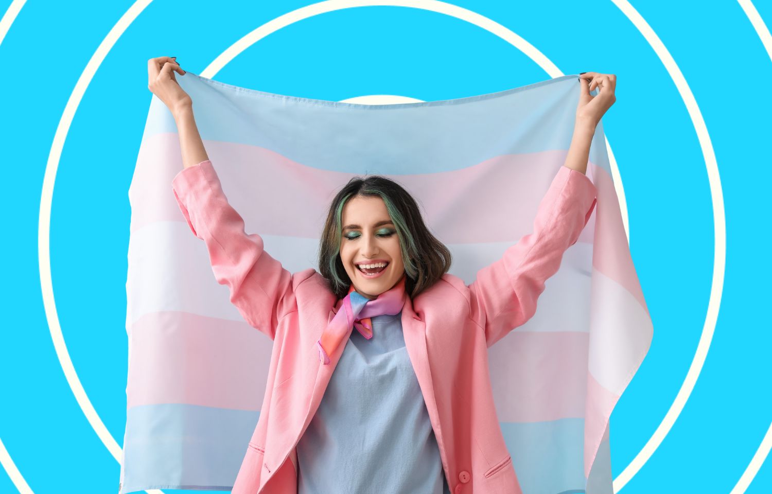 Visual of a happy young trans person holding the trans flag.