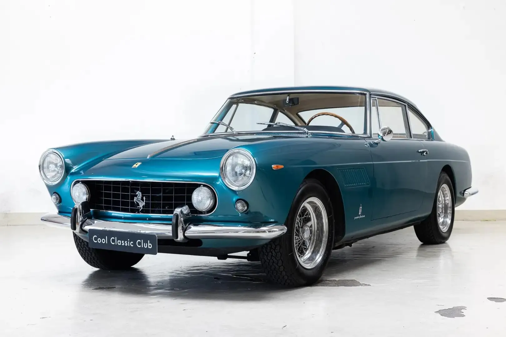 Schuin vooraanzicht van een Azurro Ferrari 250 GTE staand in Het Clubhuys