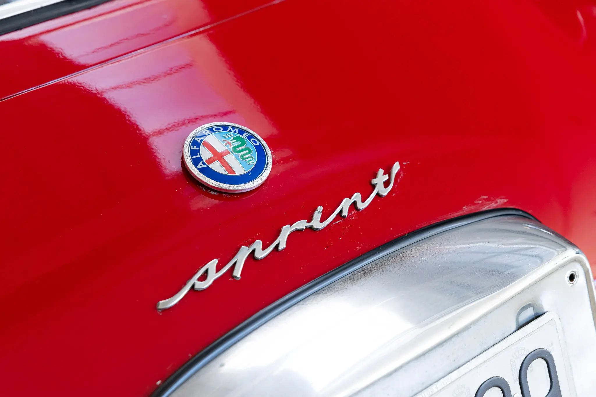 Alfa Romeo Giulia 1600 Sprint 1963 in Rosso Alfa, showcasing the badge and rear detail prominently.