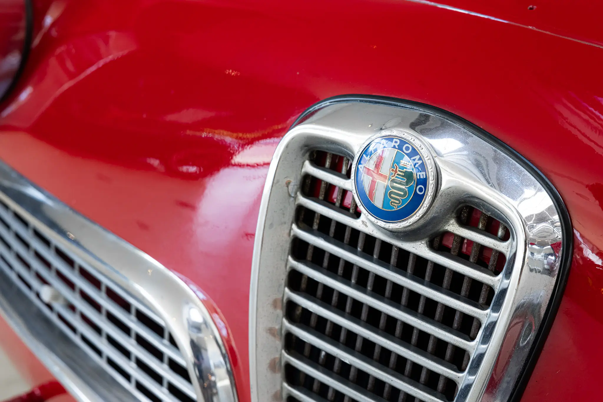 Alfa Romeo Giulia 1600 Sprint 1963 in Rosso Alfa, showing a close-up of the front grille and emblem.