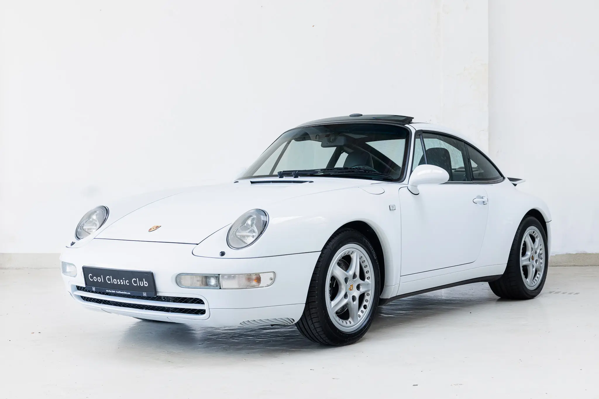 Porsche 993 Targa 1997 in Firnweiss, showcasing a dynamic front three-quarter view.