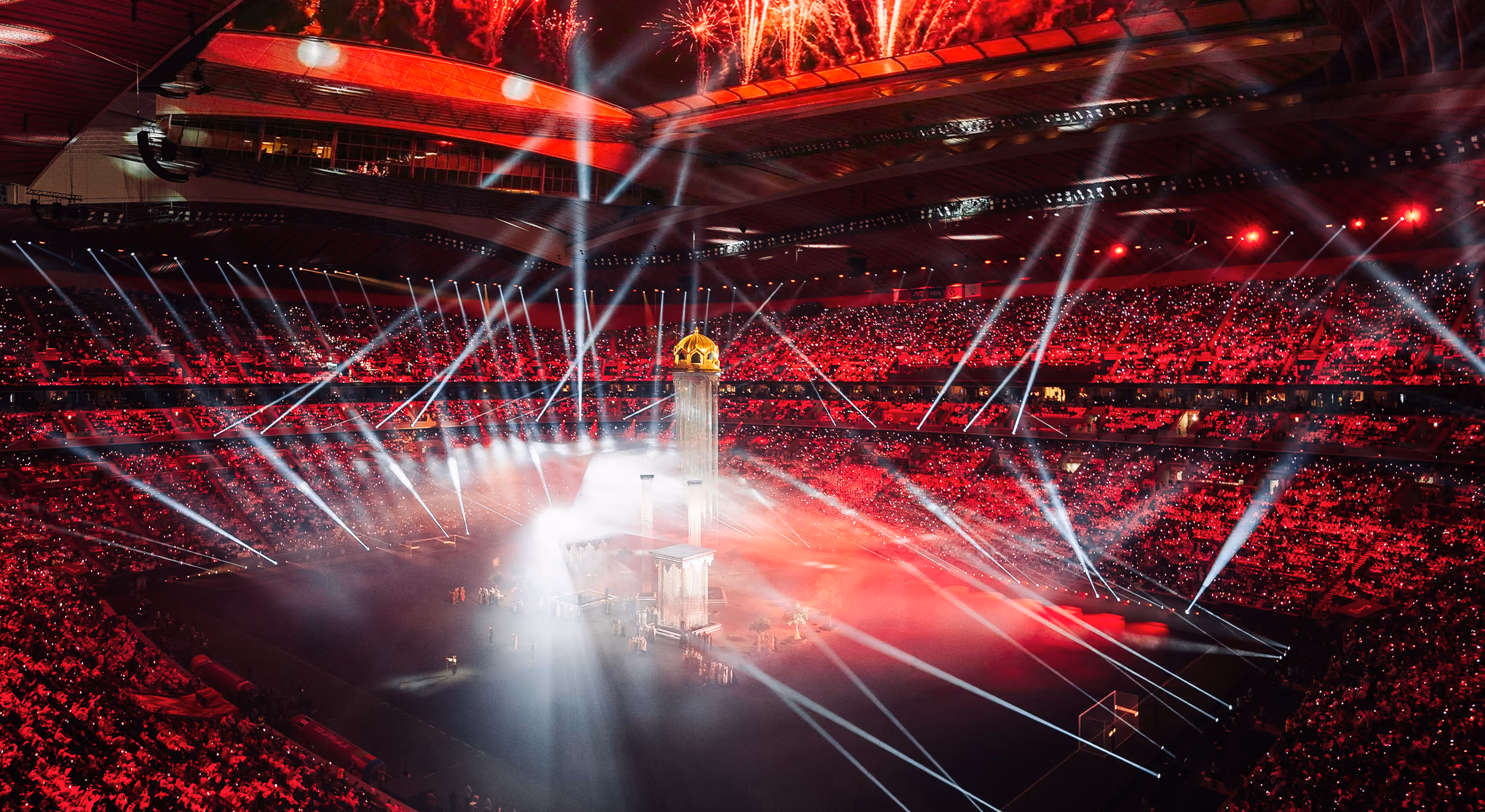 A wide shot of a packed stadium with beams of light shining down on an ornate set and performers at the Arab Cup Opening Ceremony