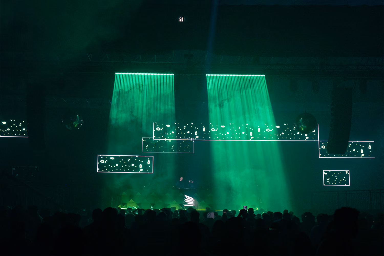 A large, energetic crowd at MDLBeast Soundstorm dances under vivid green stage lights during a DJ performance