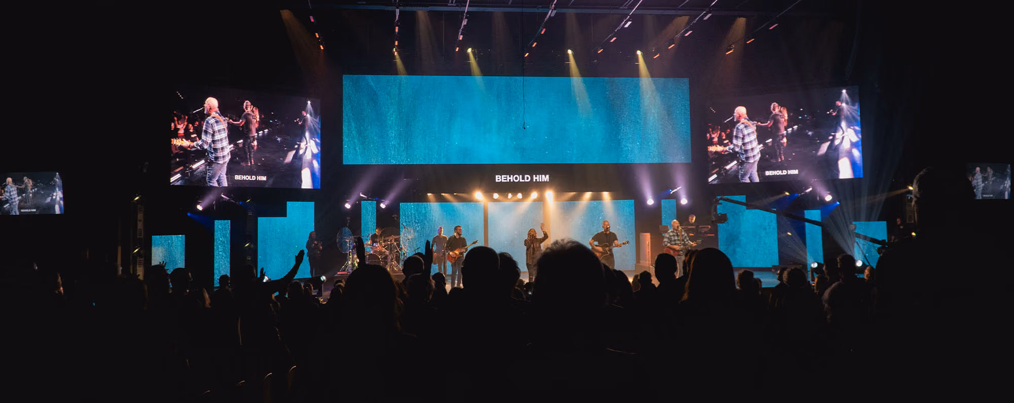 A band performing on stage at LCBC in front of several large LED screens with IMAG projection