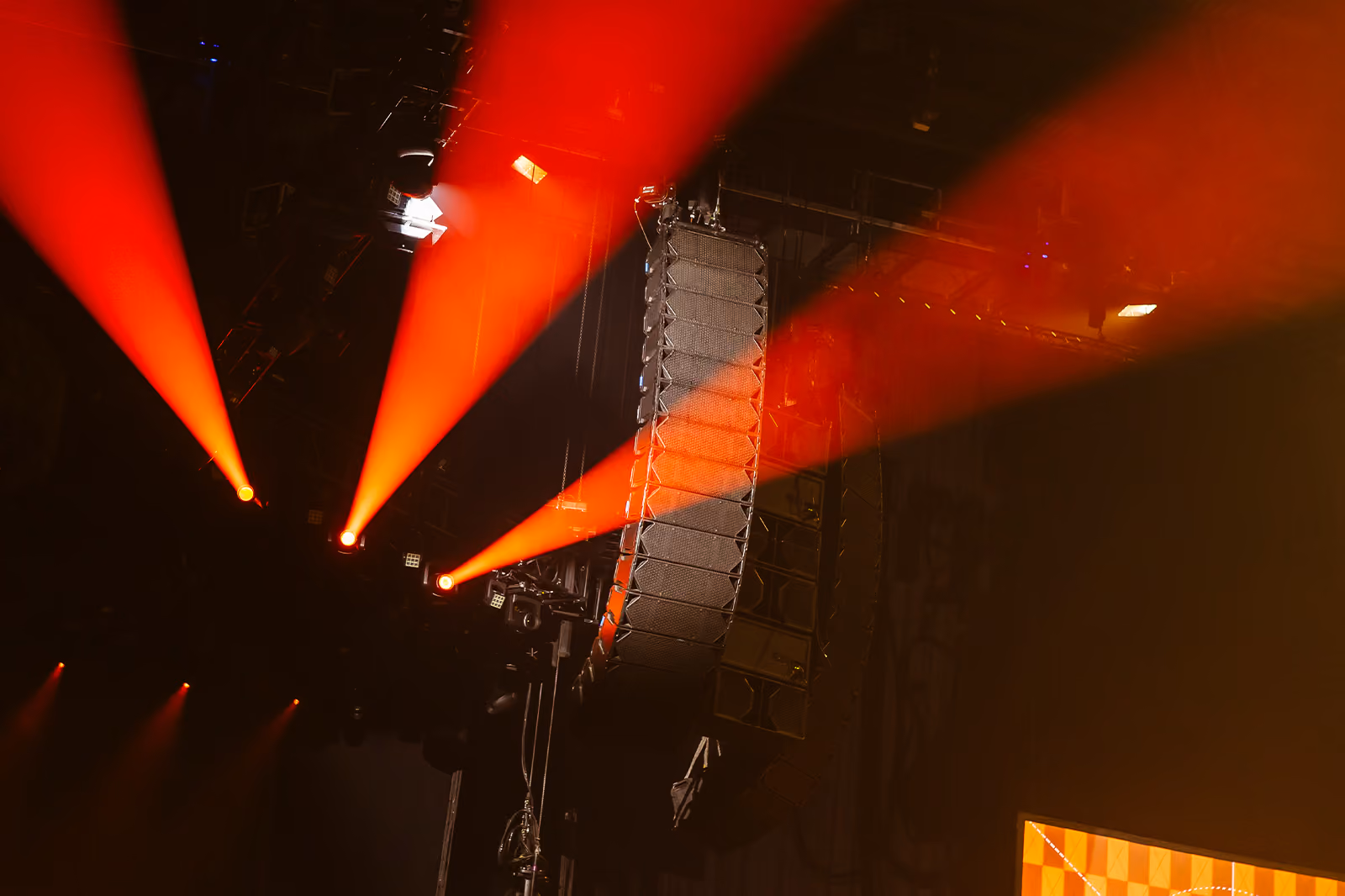 Cohesion CO12 and CP218 loudspeakers hanging at a concert with red lights beaming behind