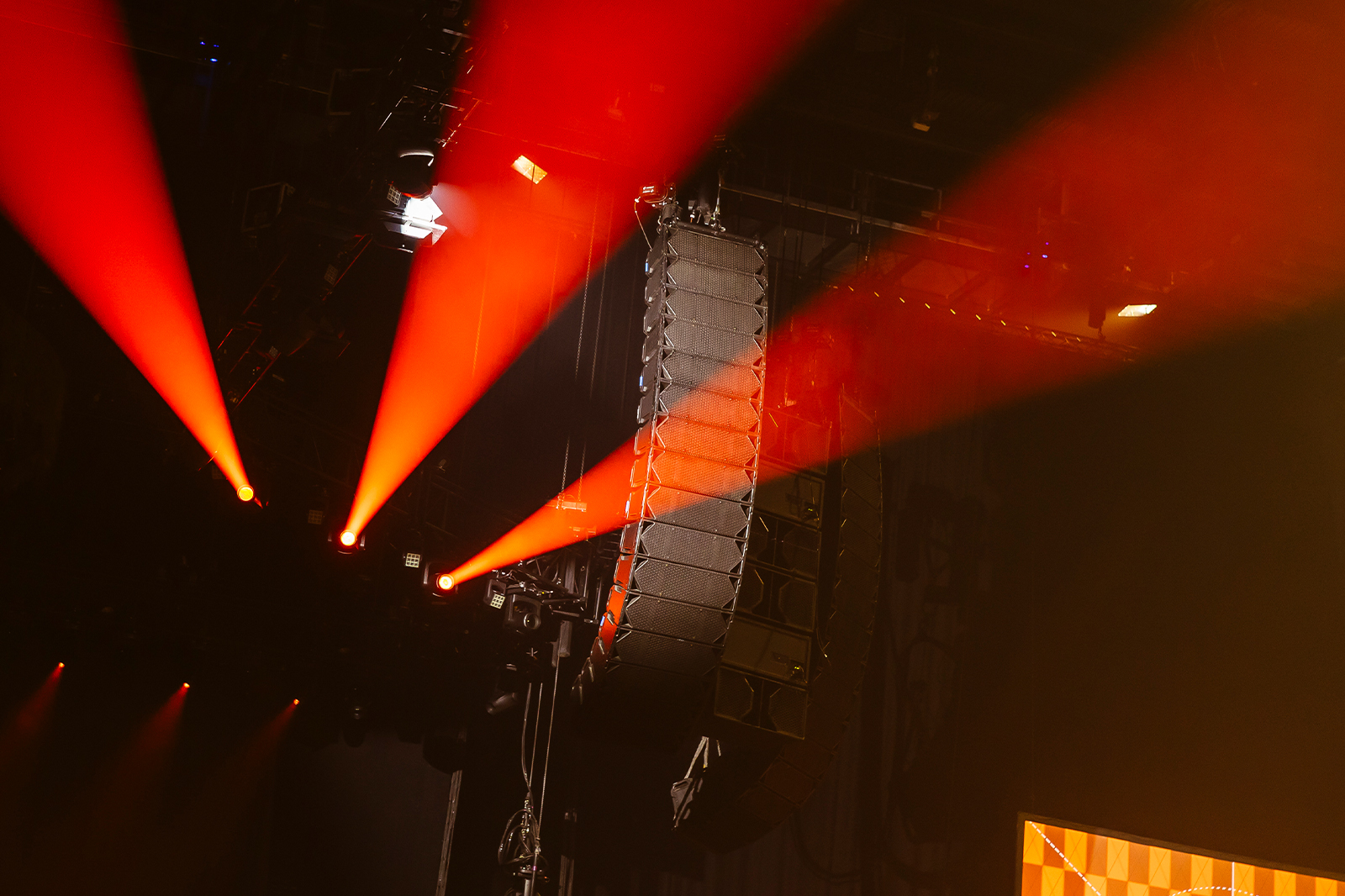 Cohesion CO12 and CP218 loudspeakers hanging at a concert with red lights beaming behind