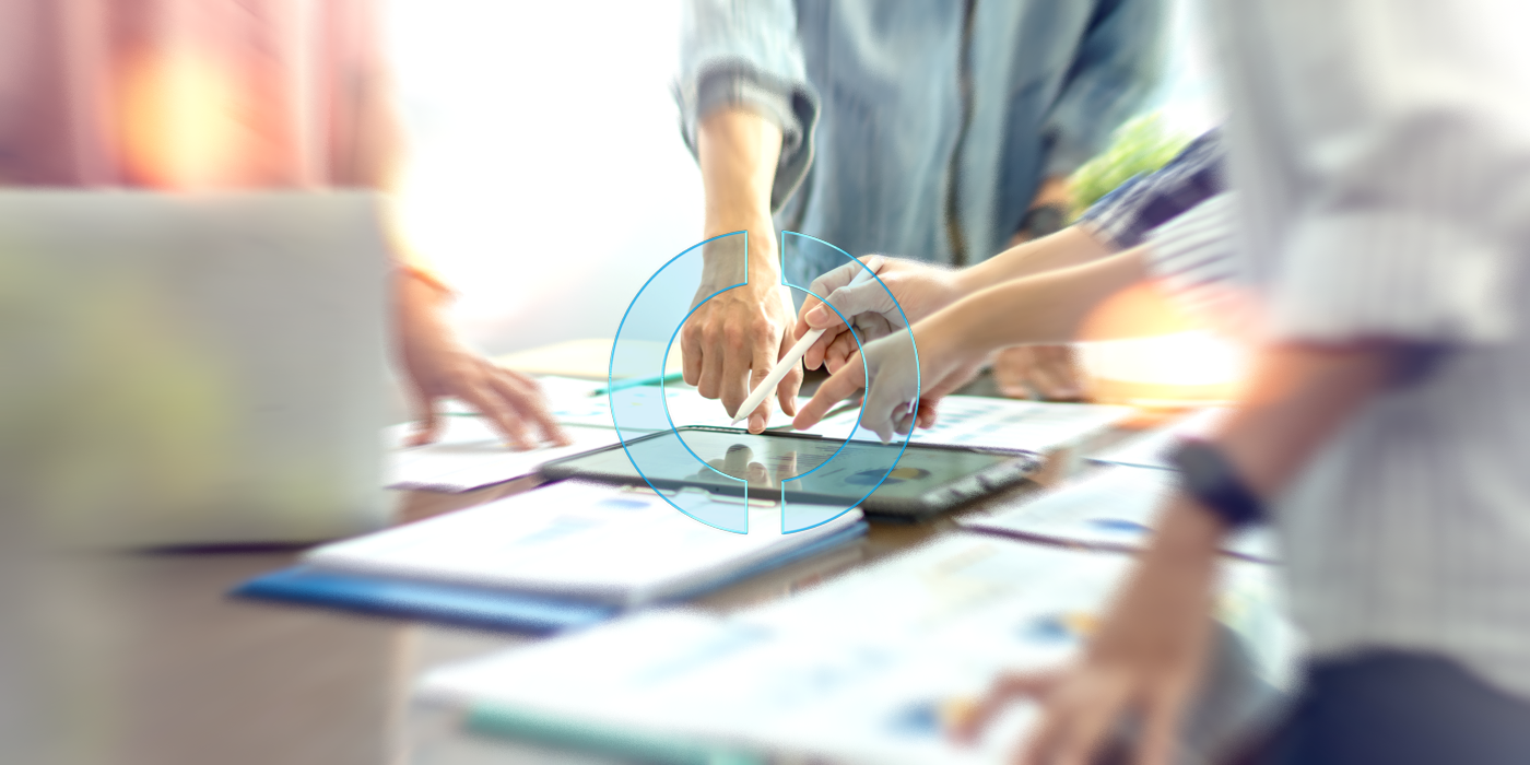 Mehrere Hände zeigen auf ein Tablet mit Auswertungen und symbolisieren die gemeinsame, datenbasierte strategische Planung zur Neuausrichtung der Marktfolge Aktiv, unterstützt durch EMPORIAS.
