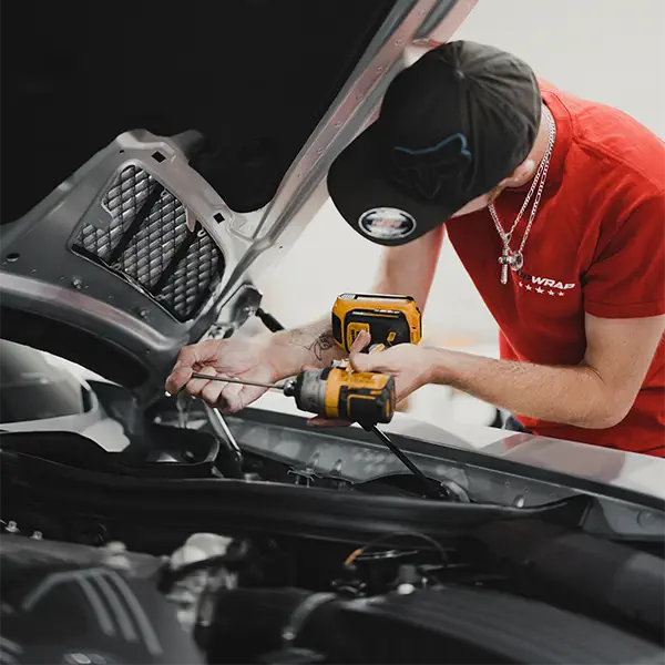 Un étudiant de la Top Wrap Academy retire un panneau de voiture à l'aide d'un outil électrique.