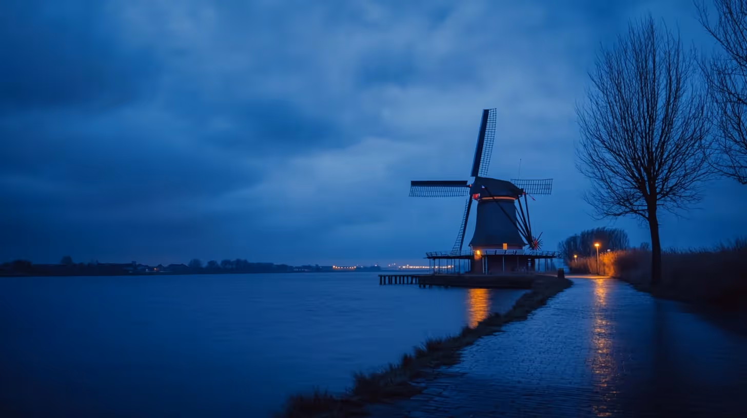 Een windmolen tegen een donkere nachtlucht, over een meer.
