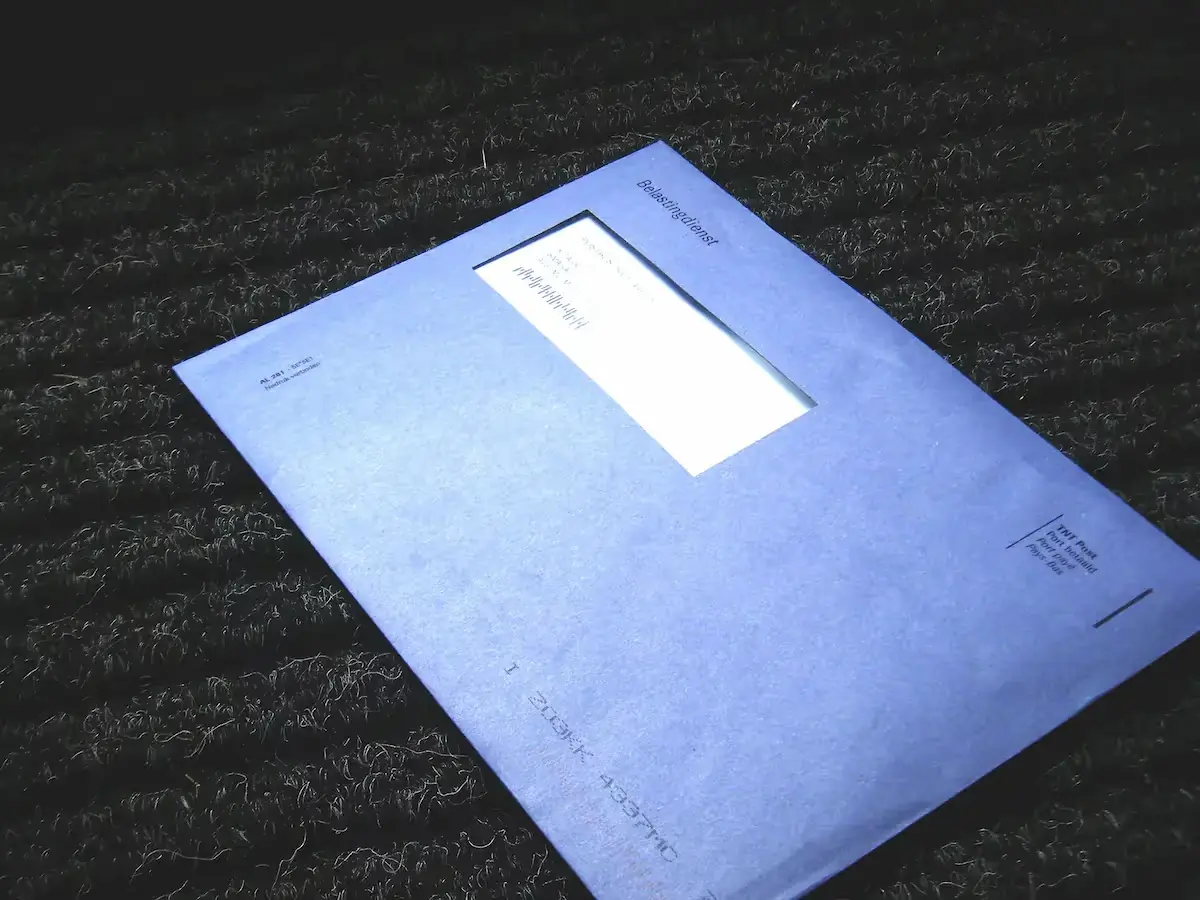 Blauwe envelop met venster ligt op donkere, harige stof. Klaarblijkelijk een bericht of document.