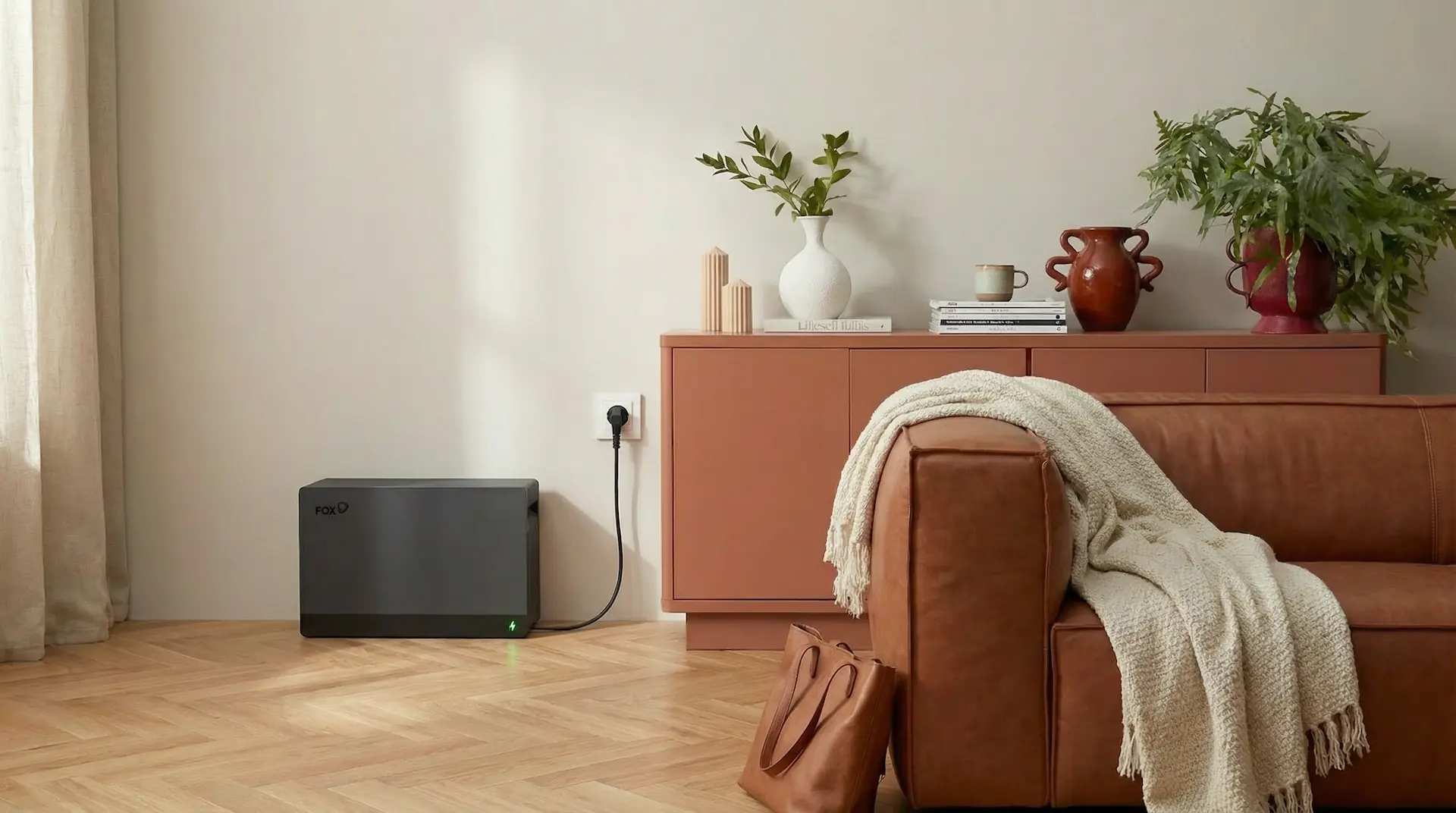 Een thuisbatterij met stekker van het merk FoxESS staat in de hoek van een moderne woonkamer.