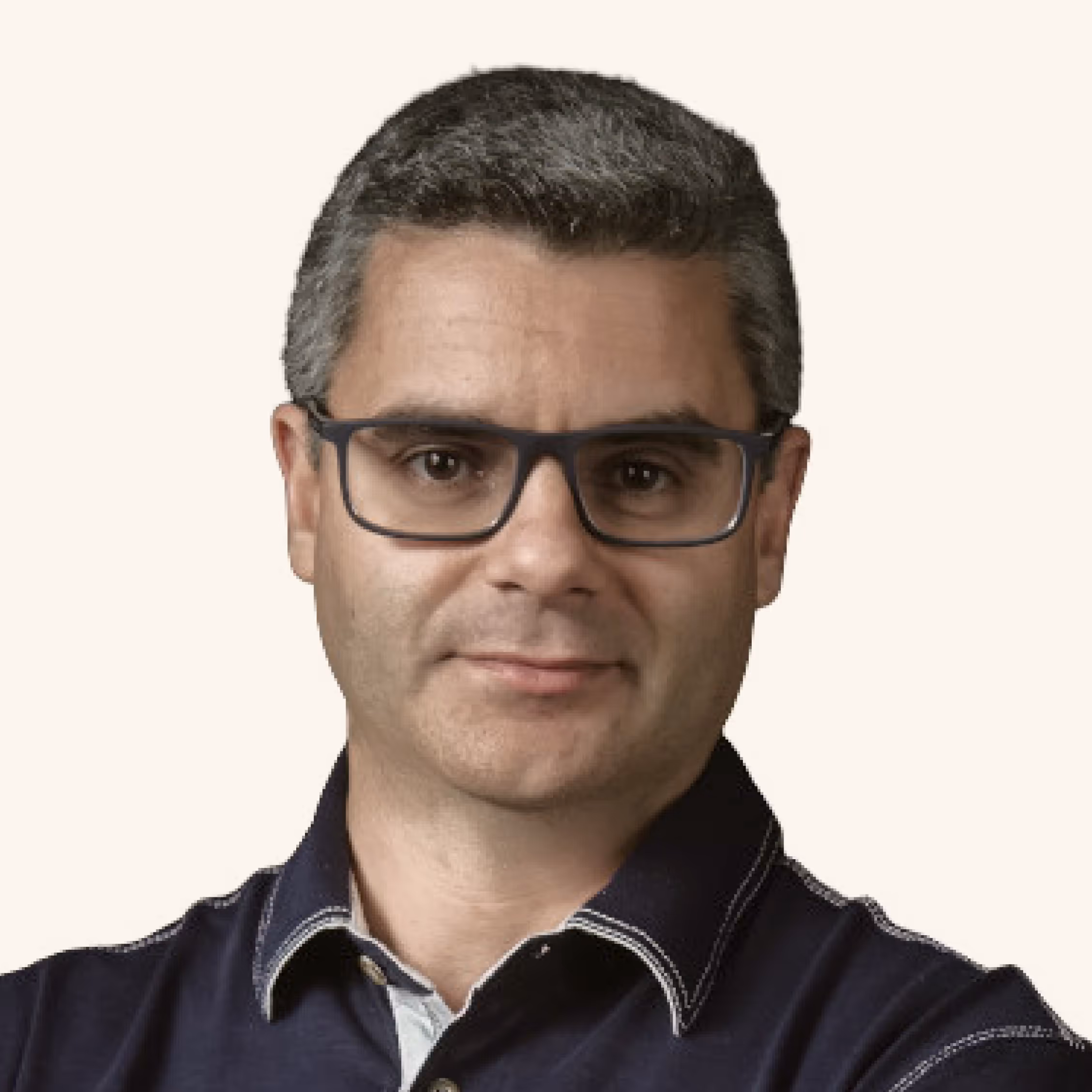 Portrait of a man with short salt-and-pepper hair wearing dark rectangular glasses and a navy collared shirt.