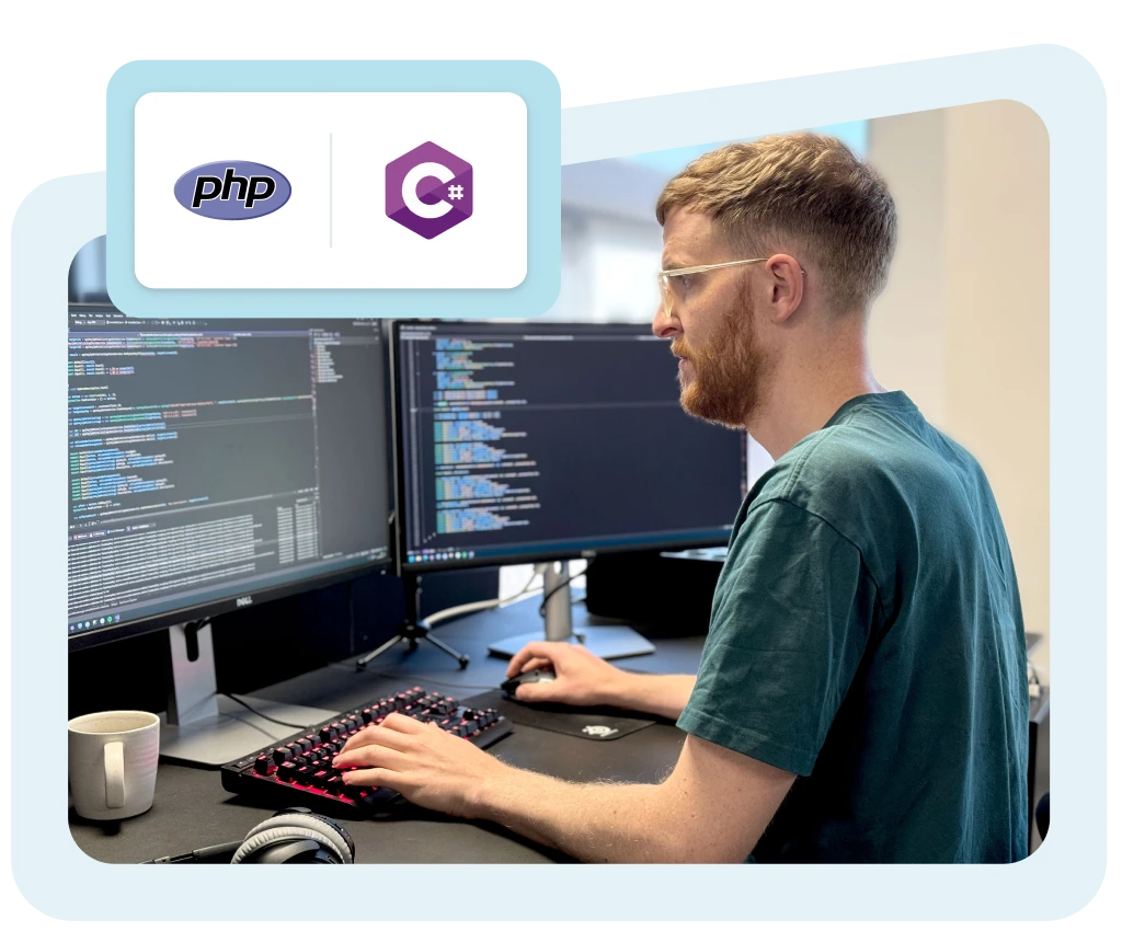 Udvikler ved skrivebord med kode på skærme, der illustrerer API-integration i PHP og C#.