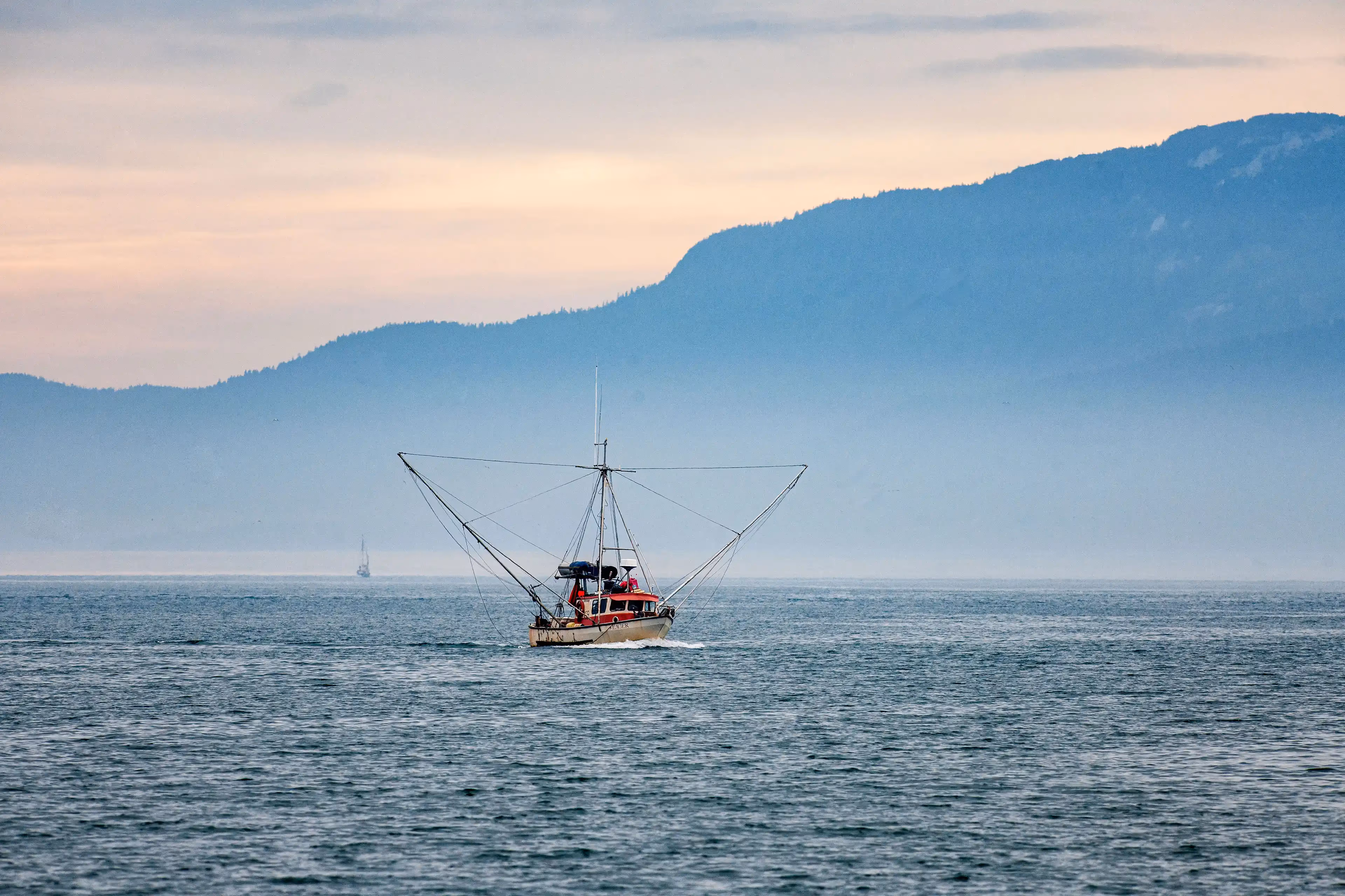 A trawler navigating through Alaska's breathtaking seascape