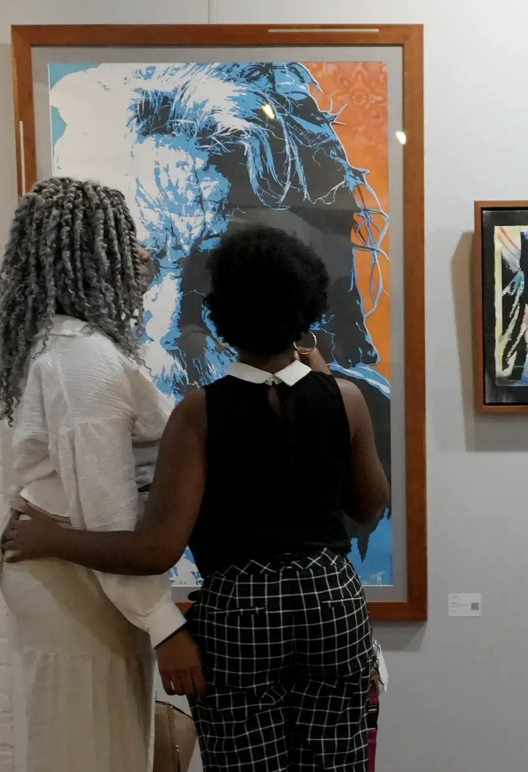 Two people seen from behind in a gallery looking at BJ's artwork.