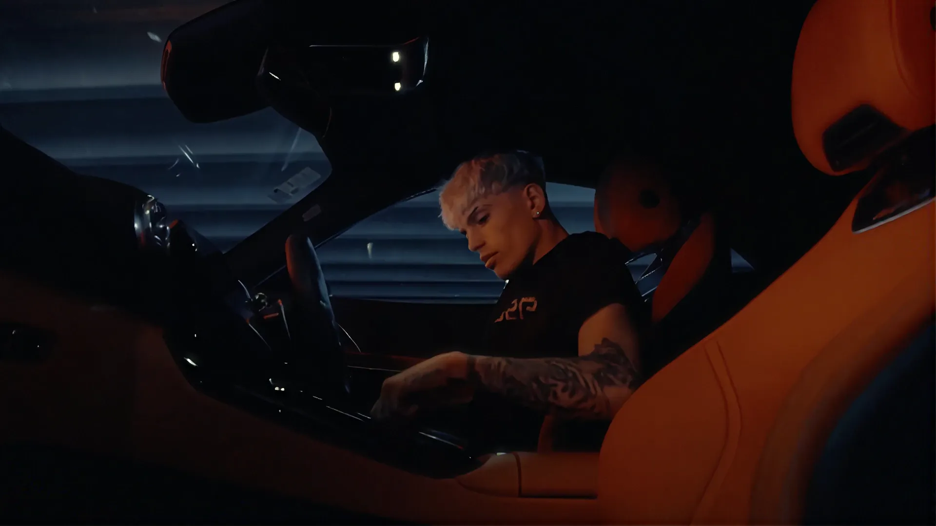 Man seated in the orange leather interior of a car at night, from a Bershka campaign